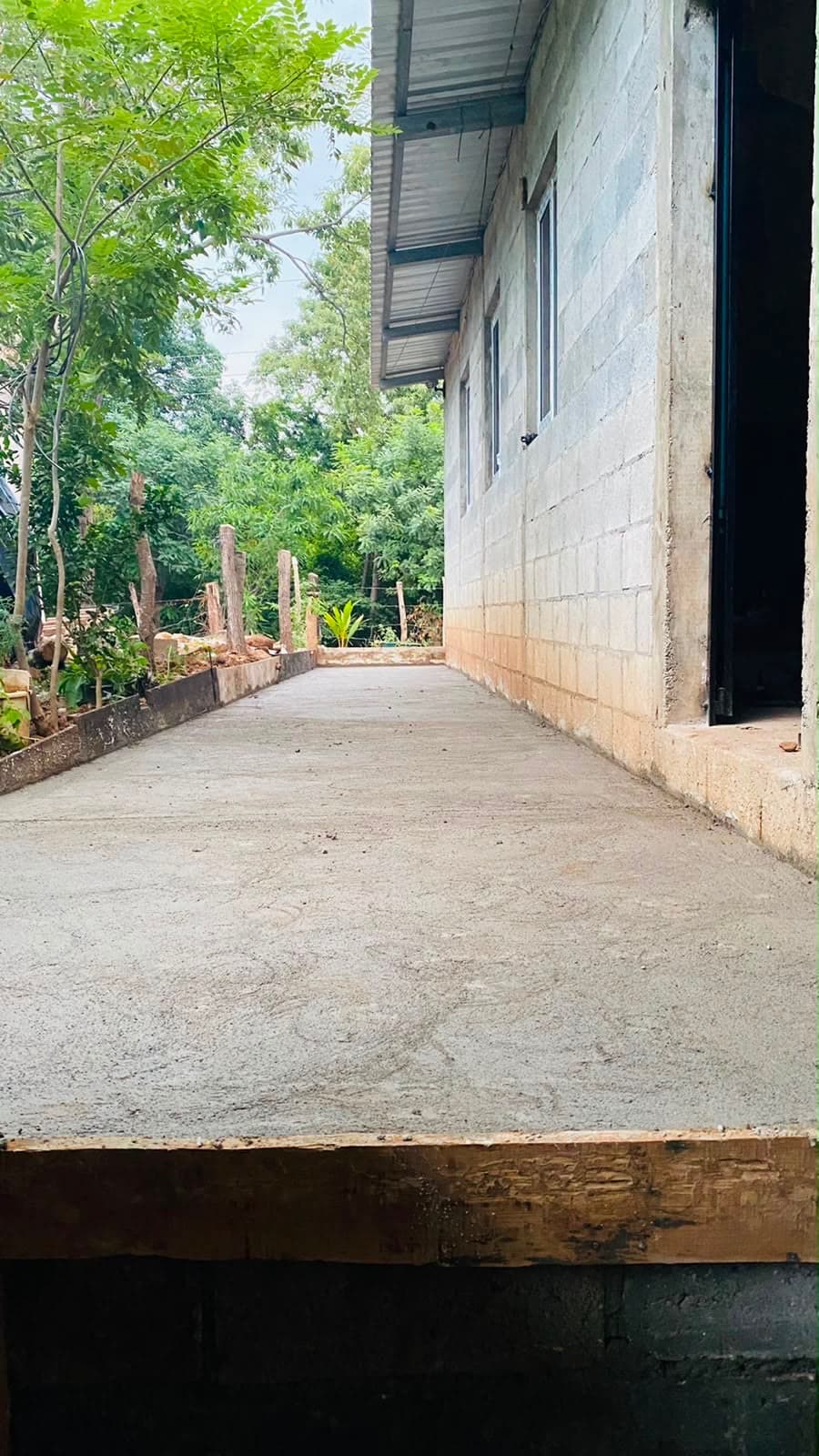 Un camino de concreto recién construido al costado de una vivienda